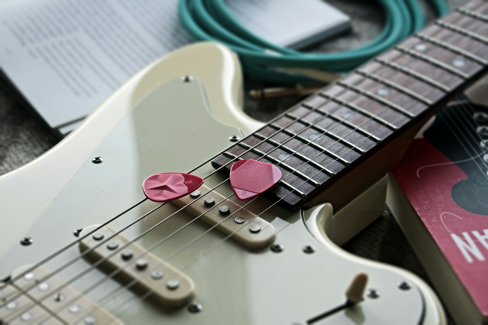 pink and white stratocaster electric guitar